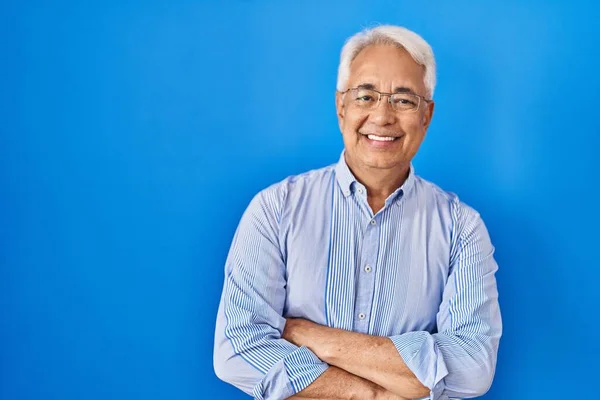 Hispanic senior man wearing glasses happy face smiling with crossed arms looking at the camera. positive person.