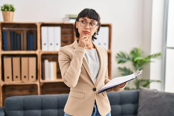 Young Hispanic Woman Working Consultation Office Serious Face Thinking Question — Stockfoto