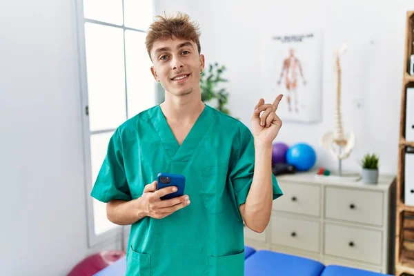 Young Caucasian Physio Man Using Smartphone Medical Clinic Smiling Happy — Stockfoto