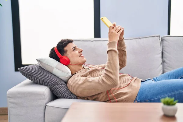 Young Non Binary Man Listening Music Lying Sofa Home — Fotografia de Stock