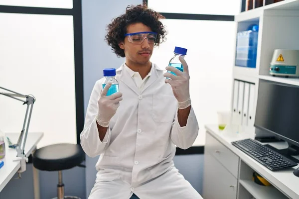 Young Hispanic Man Wearing Scientist Uniform Holding Bottles Laboratory — Stock Photo, Image