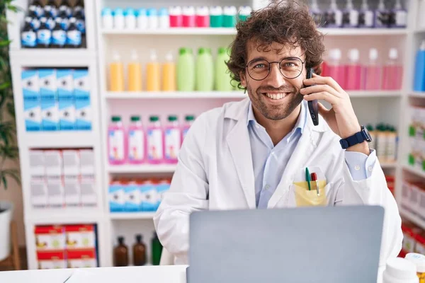Young Hispanic Man Pharmacist Talking Smartphone Using Laptop Pharmacy — Fotografia de Stock