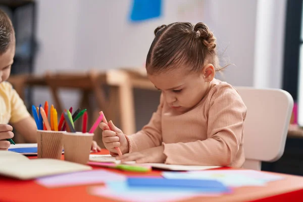 可愛いヒスパニック女子学生座っているテーブルの上に紙の上に絵を描く幼稚園 — ストック写真