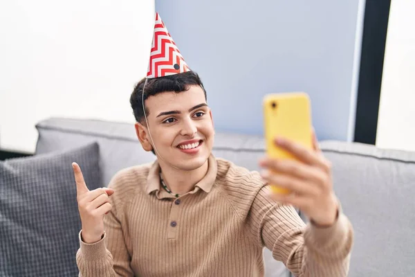Non binary person celebrating birthday doing video call smiling happy pointing with hand and finger to the side