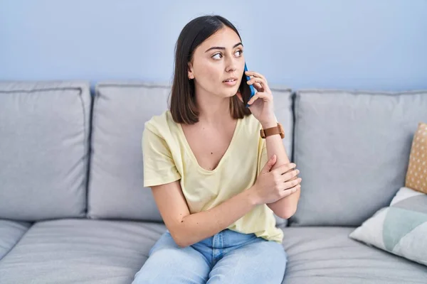 Young Hispanic Woman Serious Expression Talking Smartphone Home — Stockfoto