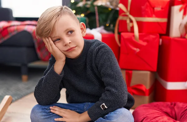 Sevimli Çocuk Evde Şüpheli Bir Ifadeyle Noel Ağacının Yanında Oturuyor — Stok fotoğraf