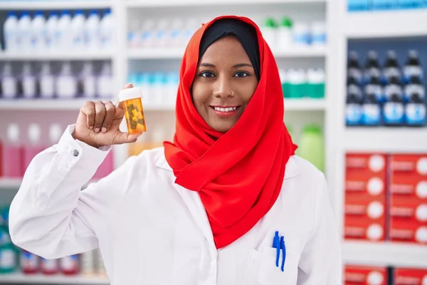Młoda Piękna Kobieta Farmaceuta Uśmiecha Się Pewnie Trzymając Butelkę Tabletek — Zdjęcie stockowe