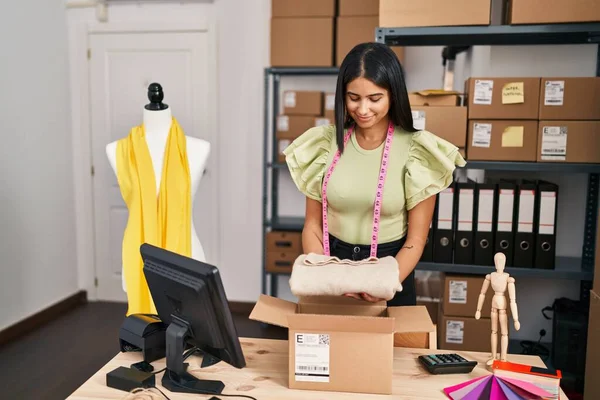 年轻的拉丁女子电子商务商人在设计工作室准备服装包 — 图库照片