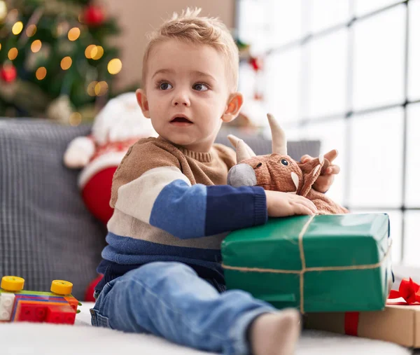 크리스마스 선물을 포장하는 스러운 갓난아기가 소파에 — 스톡 사진