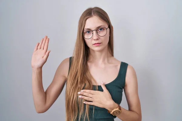 Młoda Kaukaska Kobieta Stojąca Białym Tle Przysięgająca Ręką Piersi Otwartą — Zdjęcie stockowe