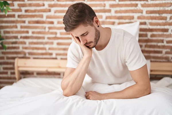 Young caucasian man stressed sitting on bed at bedroom