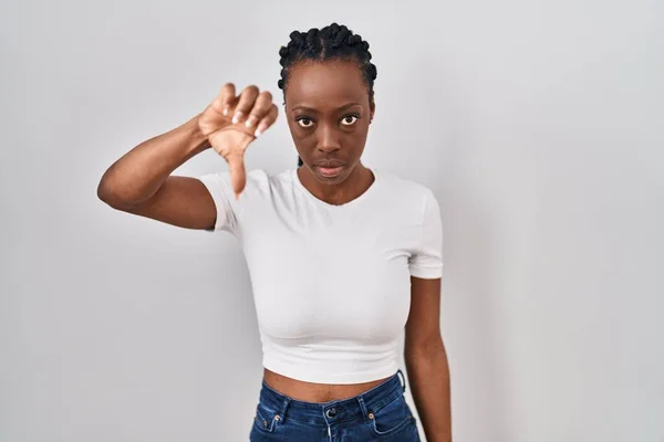 Beautiful black woman standing over isolated background looking unhappy and angry showing rejection and negative with thumbs down gesture. bad expression.