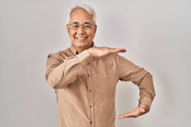 Elleriyle işaret eden gözlük takan İspanyol kıdemli bir adam. Büyük ve büyük bir işaret, ölçü sembolü. Kameraya bakıp gülümsüyor. ölçüm kavramı. 