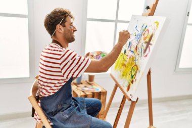 Genç İspanyol adam resim stüdyosunda kendine güvenen gülümsüyor.