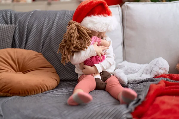 Urocza Kaukaska Dziewczyna Przytula Dziecko Lalka Siedzi Kanapie Przez Świąteczne — Zdjęcie stockowe