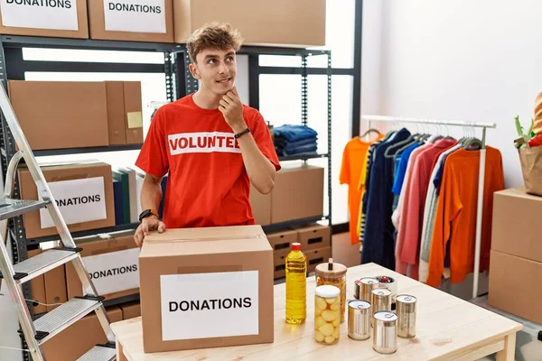 Young Caucasian Man Volunteer Holding Donations Box Hand Chin Thinking —  Fotos de Stock