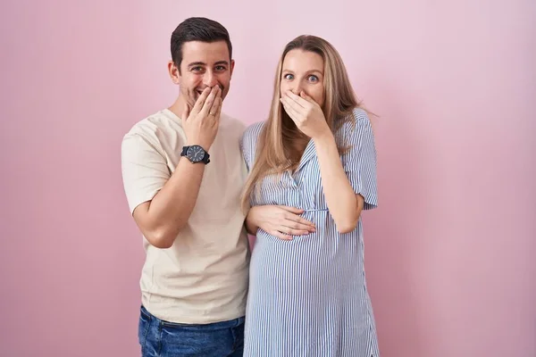 Casal Jovem Esperando Bebê Sobre Fundo Rosa Rindo Riso Embaraçado — Fotografia de Stock