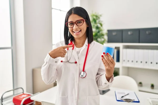 Young Hispanic Doctor Woman Holding Cotton Buds Smiling Happy Pointing — Foto de Stock