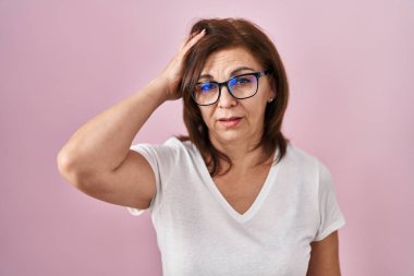Middle age hispanic woman standing over pink background looking sleepy and tired, exhausted for fatigue and hangover, lazy eyes in the morning. 