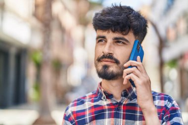Genç İspanyol adam gülümsüyor. Kendine güveniyor. Sokakta akıllı telefondan konuşuyor.
