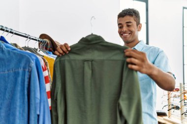 Genç İspanyol adam perakende dükkanından gömlek seçiyor.