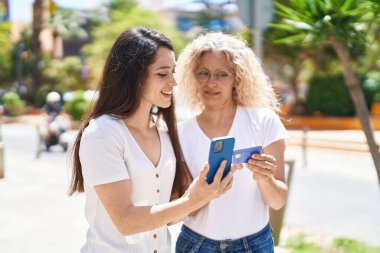 İki kadın anne-kız akıllı telefon ve kredi kartı kullanıyor.