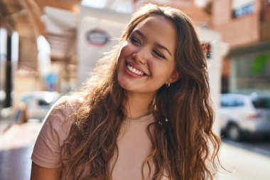 Young beautiful hispanic woman smiling confident looking to the side at street