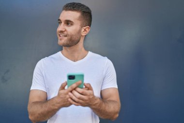 Young caucasian man smiling confident using smartphone over isolated grey background