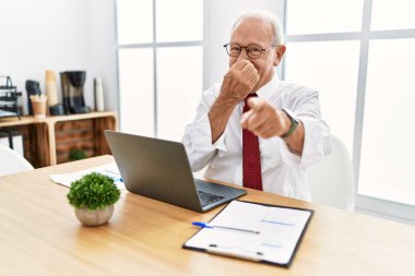 Ofiste çalışan üst düzey bir adam bilgisayarla sana gülüyor, eli ağzında kamerayı işaret ediyor, yüz ifadesi utanç verici. 