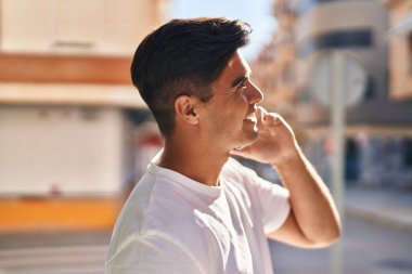 Genç İspanyol adam gülümsüyor. Kendine güveniyor. Sokakta akıllı telefondan konuşuyor.