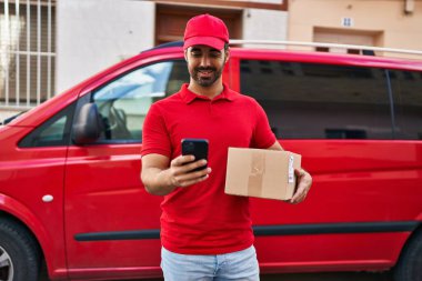 Genç İspanyol kurye sokakta akıllı telefon paketi kullanıyor.