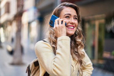 Genç bayan turist caddede akıllı telefondan konuşuyor.