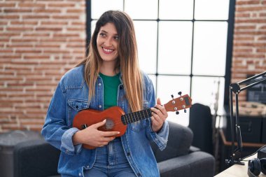 Genç İspanyol kadın müzisyen müzik stüdyosunda ukulele çalıyor.