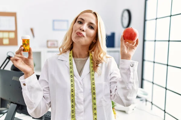 Beautiful Blonde Nutritionist Woman Holding Fat Pills Looking Camera Blowing — Stockfoto