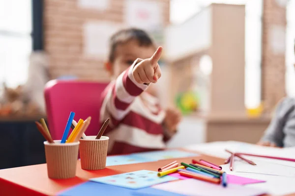 幼稚園のテーブルに座ってノートに描く愛らしい幼児の学生 — ストック写真