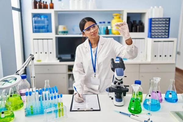研究室で働く科学者の制服を着た若いラテン語の女性 — ストック写真