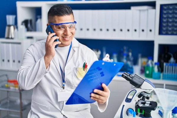 Young Latin Man Scientist Talking Smartphone Reading Document Laboratory — Stock Photo, Image