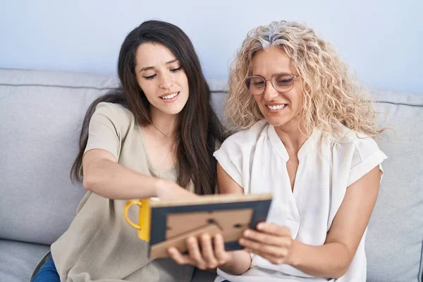 stock image Two women mother and daughter drinking coffee looking picture at home