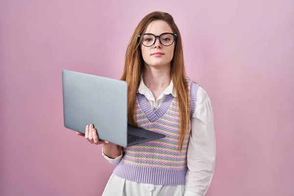 使用电脑笔记本电脑工作的年轻的高加索女人放松了 脸上有严肃的表情 简单而自然地看着相机 — 图库照片