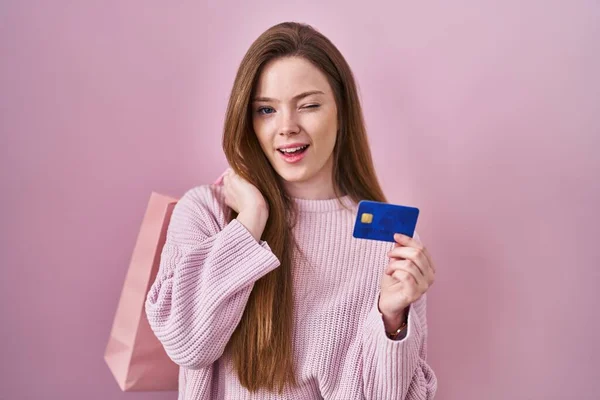Młoda Kaukaska Kobieta Trzyma Torba Zakupy Karta Kredytowa Mruga Patrząc — Zdjęcie stockowe