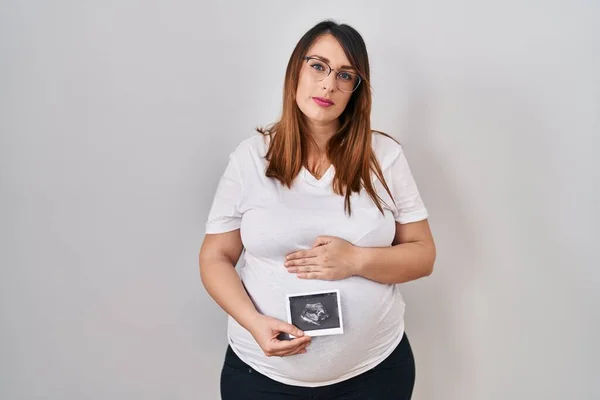抱着婴儿体格检查的孕妇面带严肃的表情放松了下来 简单而自然地看着相机 — 图库照片