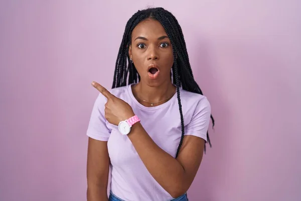 African American Woman Braids Standing Pink Background Surprised Pointing Finger — Stockfoto