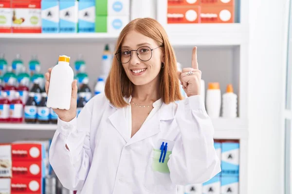 Young Redhead Woman Working Pharmacy Drugstore Holding Sun Screen Surprised — Zdjęcie stockowe