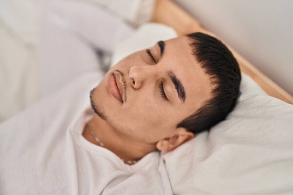 Молодой человек лежит на кровати и спит в спальне.