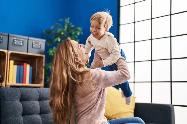 Mother and son holding kid on air sitting on sofa at home