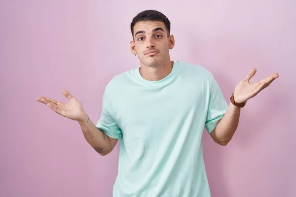 Handsome Hispanic Man Standing Pink Background Clueless Confused Expression Arms — Stock Photo, Image