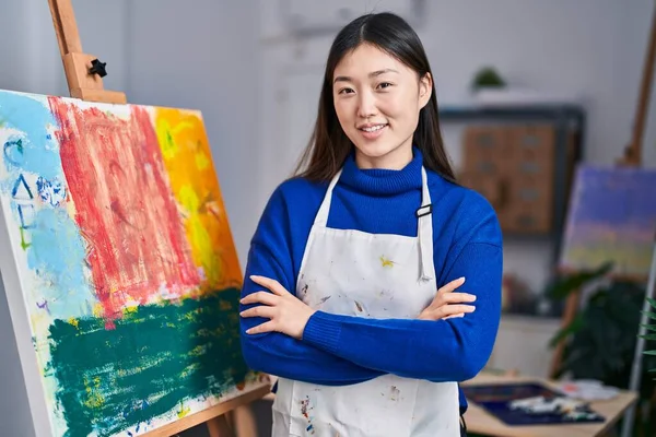 Chinese woman artist smiling confident standing with arms crossed gesture at art studio