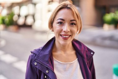 Sokakta kendinden emin gülümseyen genç bir kadın