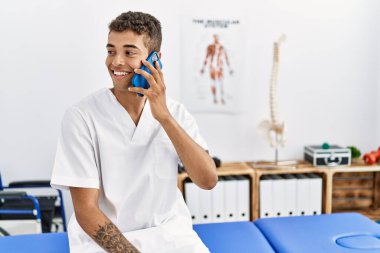 Fizyoterapi odasında konuşan genç bir İspanyol fizyoterapist.