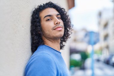 Sokakta ciddi bir ifadeyle dikilen genç Latin adam.